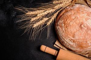 Beautiful fresh baked bread with wheat grains on a dark concrete background