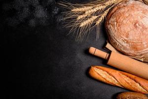 Beautiful fresh baked bread with wheat grains on a dark concrete background photo