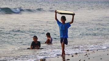 documentación de surfistas en acción al atardecer con un color dorado y oscuro, desenfocado y oscuro en la playa de senggigi lombok, oeste de nusa tenggara indonesia, 27 de noviembre de 2019 foto