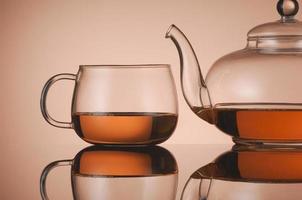 Transparent glass teapot and cup with tea photo