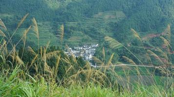 los hermosos paisajes de las montañas con el bosque verde y el pequeño pueblo como fondo en el campo de China foto