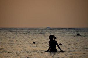 mujer en el mar durante la puesta de sol foto