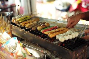 primer plano varios tipos de bolas y salchichas a la parrilla por el carbón. comida de la calle foto