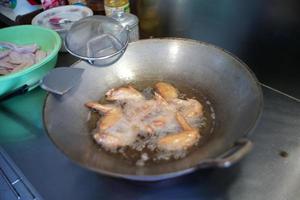 Selective focus on many pieces of chicken wings deep fried in the boiled vegetable oil. photo