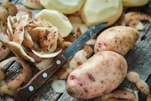 Potato peeling on the rough wooden boards of a country table photo