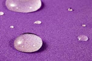 Fantastic and Beautiful Macro Photo of Water Droplets on Purple Background. Beautiful Transparent Rainwater Drops, Macro, Copy Space. Bright Colorful Art Image of Nature.