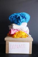 Donation box with stack of clothes against black background photo