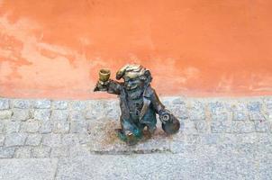 wroclaw, polonia, 7 de mayo de 2019, franek enano borracho alcohólico con botella y vaso, el famoso gnomo en miniatura de bronce con escultura de sombrero es un símbolo de wroclaw en el antiguo centro histórico de la ciudad foto