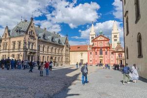 Prague, Czech Republic, May 13, 2019 courtyard square with St. George's Basilica towers of the Prague Castle buildings, walking people tourists, Mala Strana Lesser Town, Bohemia