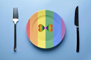 Two hearts in LGBT flag colors in plate. Romantic gay community dating. Dinner without discrimination against sexual minorities. LGBT wedding banquet preparation. photo