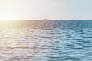 barco de pesca en el mar, barco de arrastre solitario va al puerto para vender capturas de pescado, clima claro y soleado, hermoso horizonte de paisaje marino. foto