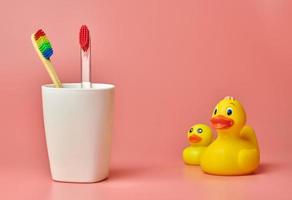 Two toothbrush and duck toy, copy space. Personal care tool for protect oral cavity, remove plaque and tartar. photo