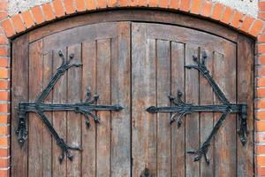 patrón forjado en la puerta con elementos decorativos, entrada antigua, puerta de madera maciza y pesada de la iglesia o catedral. foto