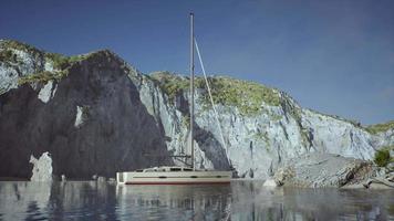 White yacht anchored in a bay with rocky cliffs video