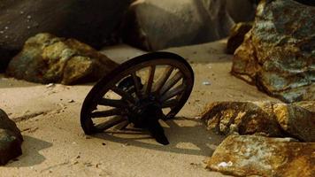 rueda de carreta de madera antigua en la playa de arena
