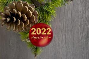 New year concept. Fir cone with New Year's red ball on a wooden background.