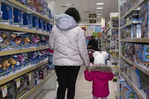 zhytomyr, ucrania - 16 de enero de 2022 una niña adorable compra juguetes. mamá e hija en la tienda de juguetes para niños. foto