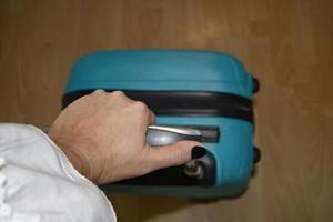 Traveler hand holding suitcase in an airport. The concept of Vacation and Rest from Work. photo