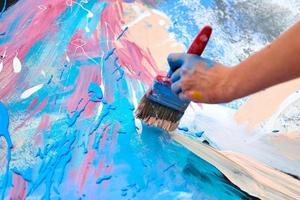 arte de expresión de pintura por goteo sobre lienzo con colores azul, rosa y beige, actuación artística del artista