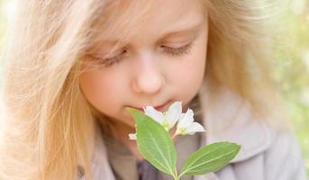 Blonde little girl sniffs Jasmine flowers photo