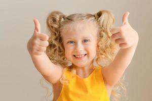 Close-up portrait of funny little girl, showing double thumbs-up