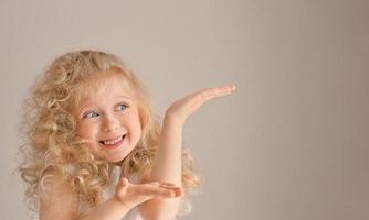 Blonde caucasian girl amazed and smiling while presenting with her hands photo