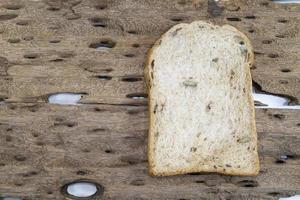 Whole wheat bread slice have rice grain on wood background.