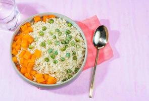 brown rice in bowl and vegetable bean peas carrot on pink background. photo