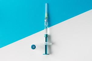 Syringe with medical vial for injection on blue and white background. Top view. photo