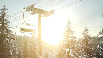 lege skilift. stoeltjeslift silhouet op hoge berg boven het bos bij zonsondergang