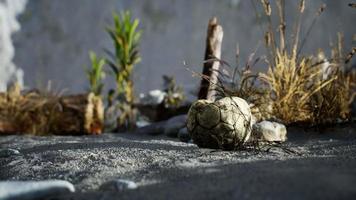 uma velha bola de futebol rasgada jogada encontra-se na areia da praia do mar video