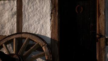 rueda de madera vieja y puerta negra en la casa blanca