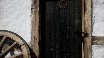 rueda de madera vieja y puerta negra en la casa blanca video