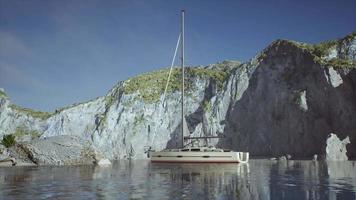 White yacht anchored in a bay with rocky cliffs video