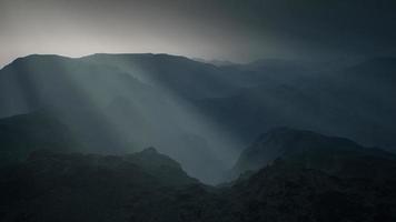 zwart rotsachtig bergsilhouet in diepe mist