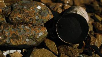 baril de métal détruit rouillé sur les rochers de la plage