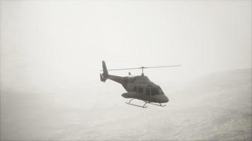 extreme slow motion flying helicopter near mountains with fog
