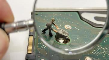 close-up computer equipment, handheld magnifying glass and miniature workers photo