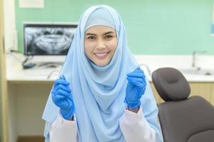 joven dentista musulmana sosteniendo invisalign en clínica dental, chequeo de dientes y concepto de dientes sanos foto