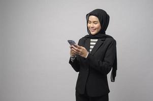 retrato de una mujer hermosa con hiyab usando un teléfono celular con fondo blanco foto