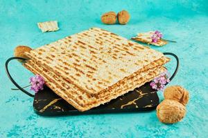 Pesach celebration concept - jewish Passover holiday. Matzah on stand made of marble with walnuts and wildflowers photo