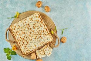 Pesach celebration concept - jewish Passover holiday. Matzah on wooden stand with nuts and wildflowers
