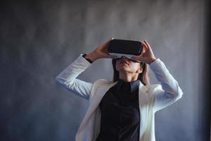 mujer feliz con fondo negro en el estudio obtiene la experiencia de usar auriculares de realidad virtual vr-glasses. foto