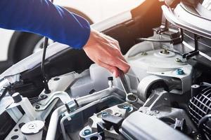 Hands of car mechanic with wrench in garage photo