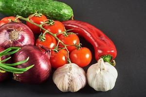 blue onion and garlic, tomato and cucumber on a black background. photo