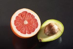 Fresh and juicy grapefruit and avocado isolated on a black background.
