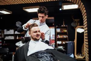 hombre peluquero haciendo corte de pelo barba hombres adultos en la peluquería de hombres foto