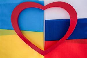las dos banderas de rusia y ucrania sostienen el corazón. foto