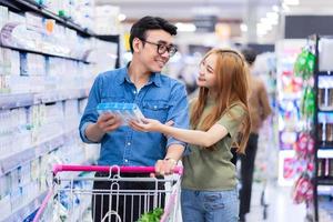 recién casados asiáticos comprando comestibles en el supermercado foto