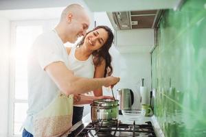 feliz pareja joven preparándose en la estufa foto